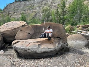a man sitting on a huge speroid boulder